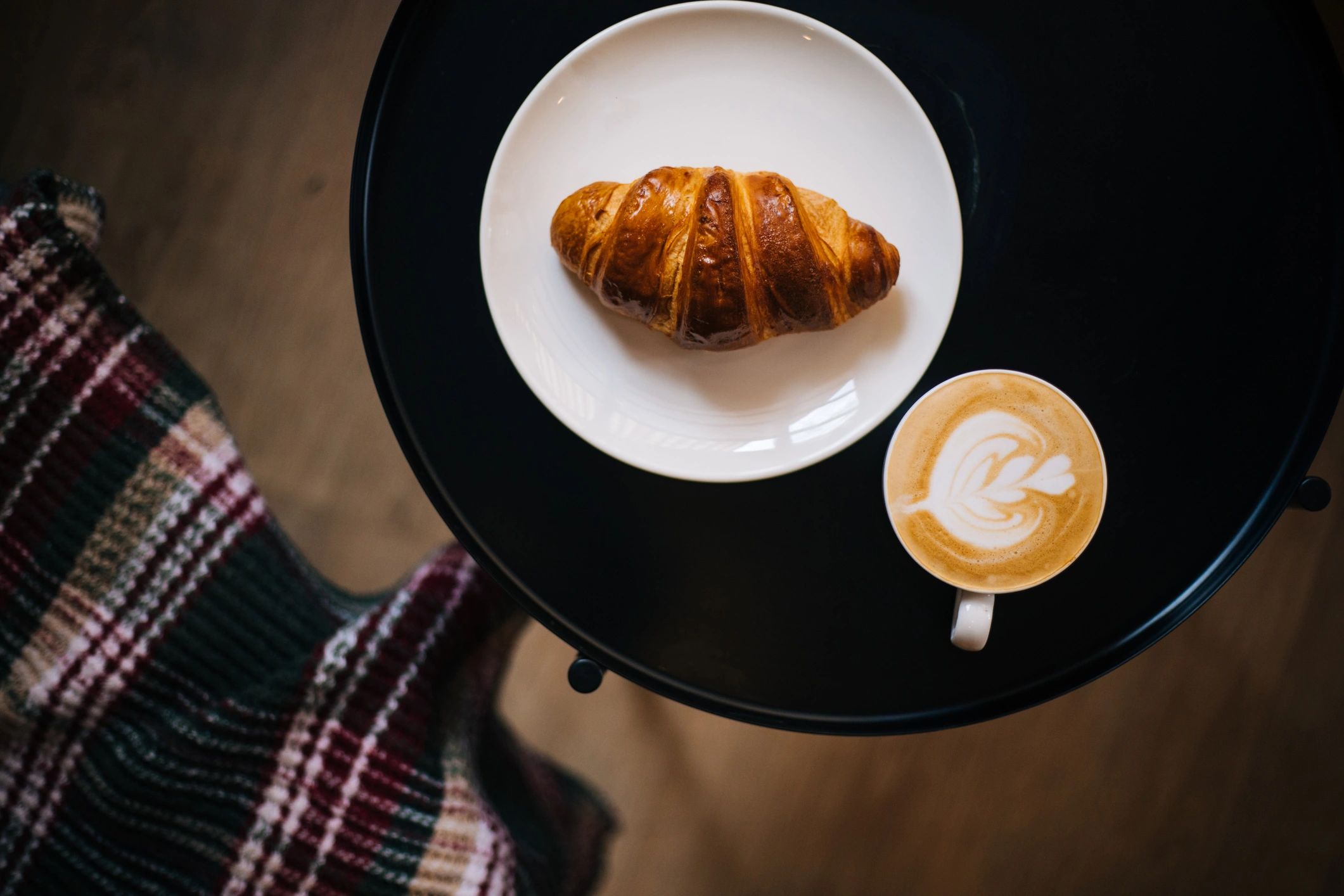 Coffee and croissant on a wooden table.
