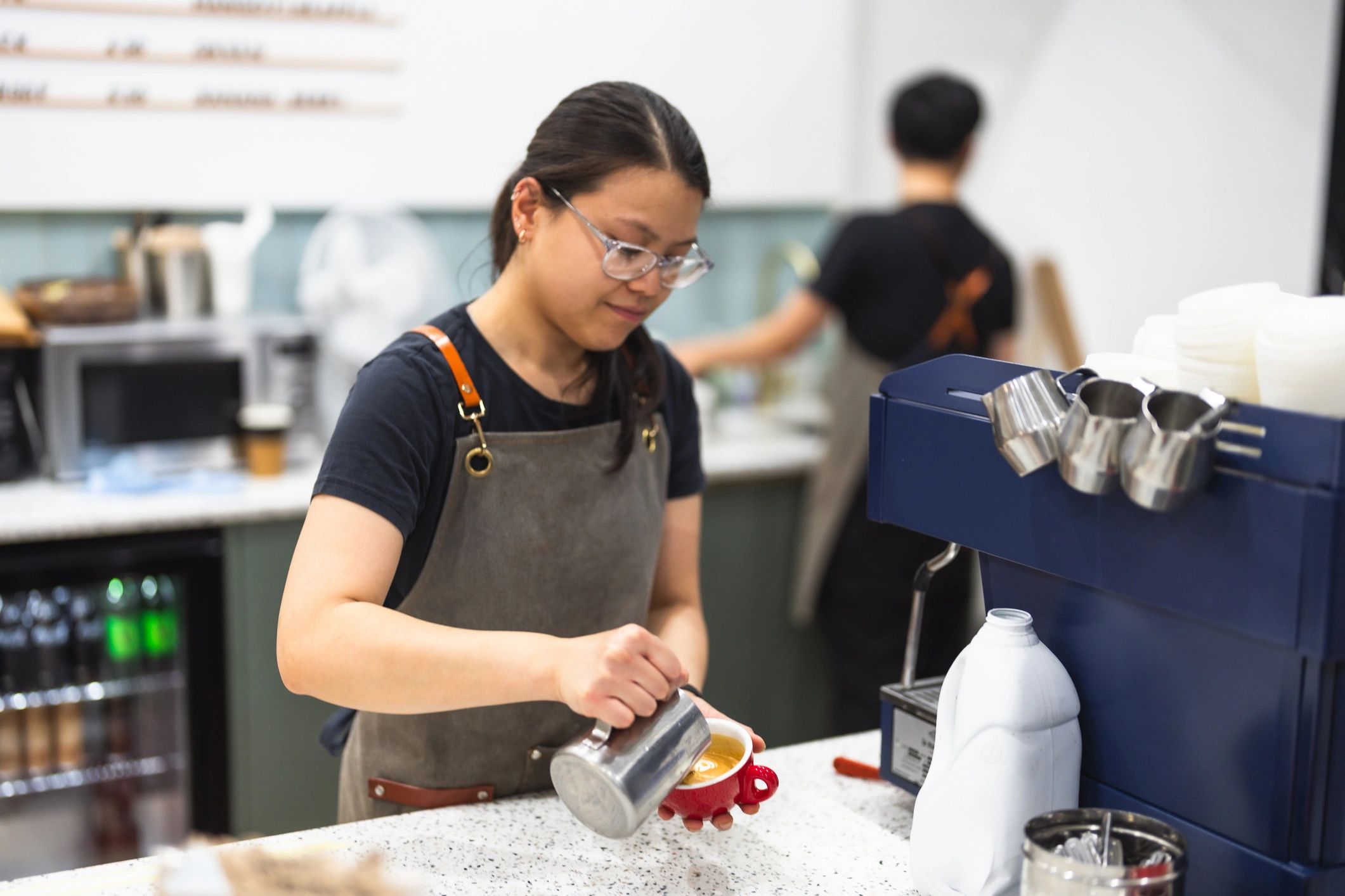 Barista making latte art in a cozy cafe.