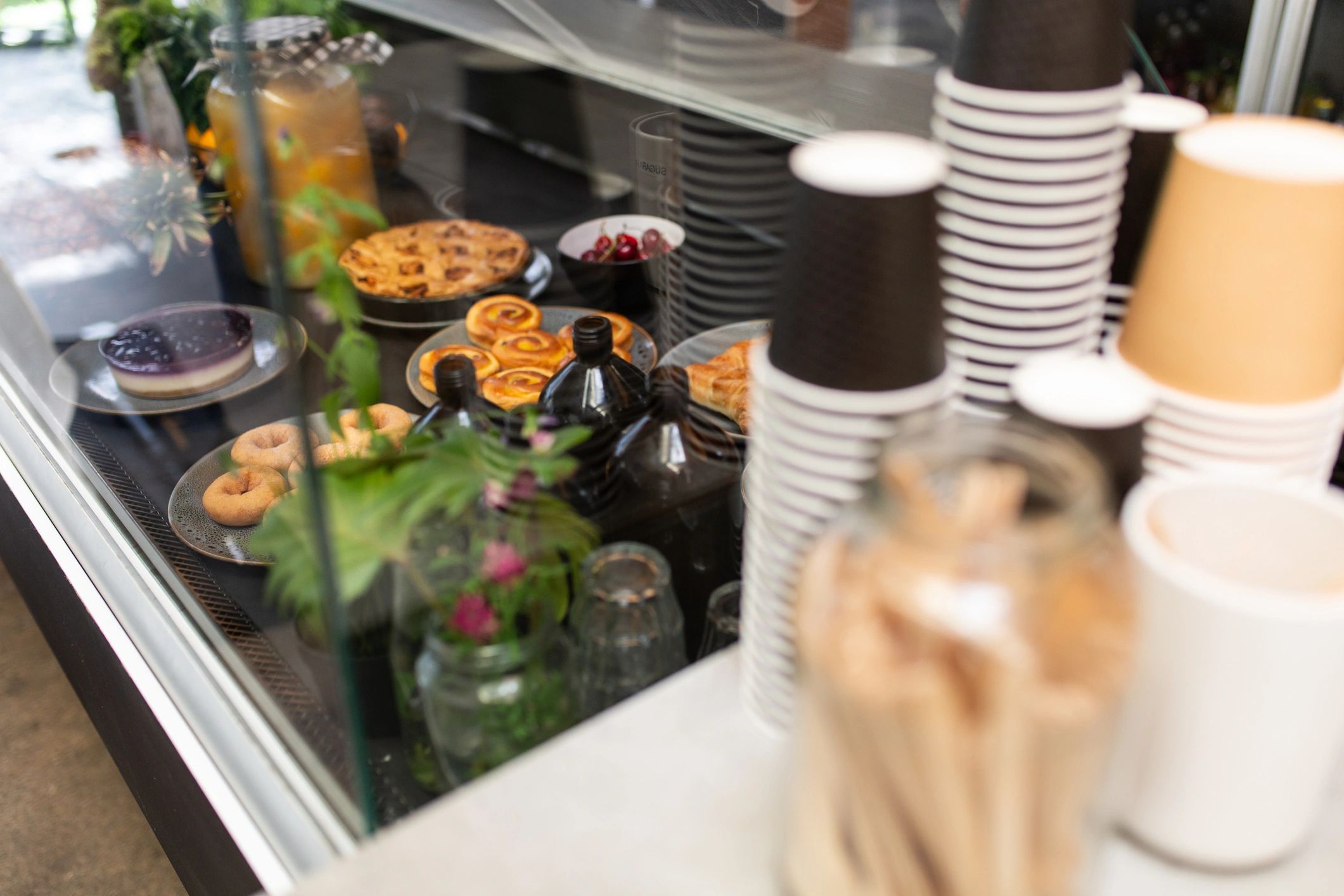 Cafe display cabinet beside takeaway cups.